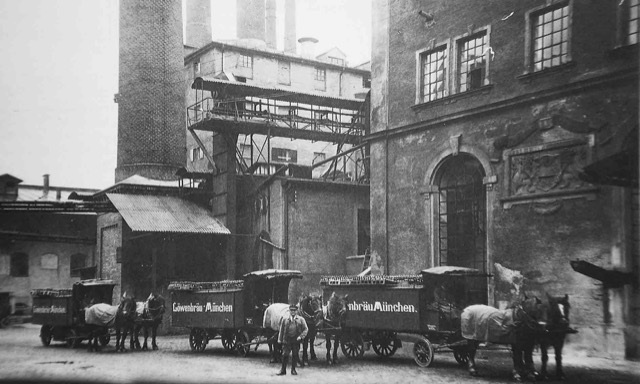 Brauereihof mit Fuhrwerken, ca. 1925 Historische Schwarz-Weiß-Aufnahme: vier Pferdefuhrwerke mit Bierfässern im Hof der Unionsbrauerei, beschriftet mit Löwenbräu und Unionsbräu