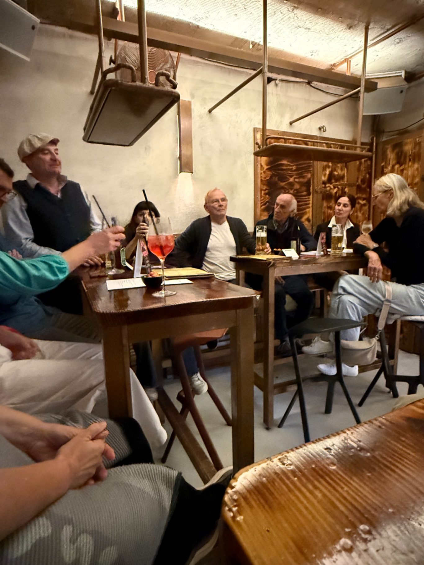 1. Unionsbäu-Stammtisch in der Boazn / 15.10.26 Eine Gesprächsrunde sitzt an hohen Holztischen, vor ihnen Bier und ein Aperitif-Glas. Alle blicken in dieselbe Richtung.